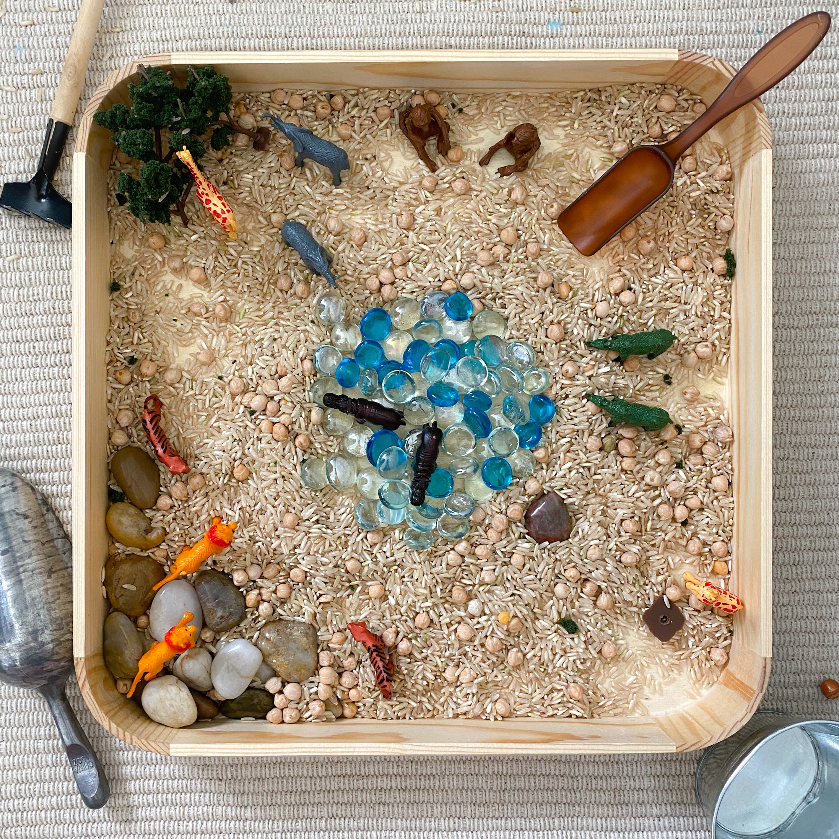 Top-down view of the safari bin with marbles, rice and safari animals arranged as if in the wild.