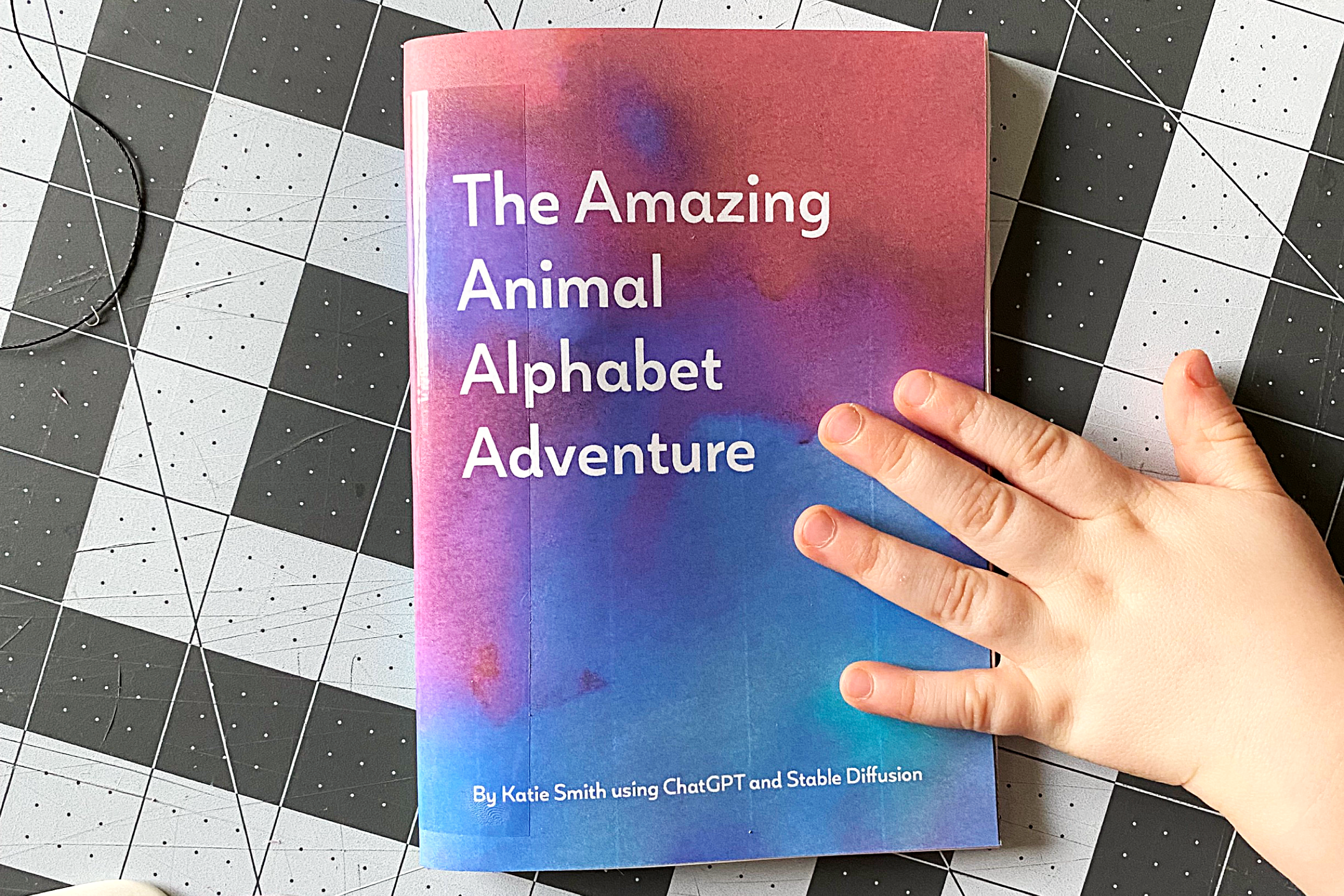 \"The Amazing Animal Alphabet Adventure\" book with a little boy's hand grabbing it off the table.